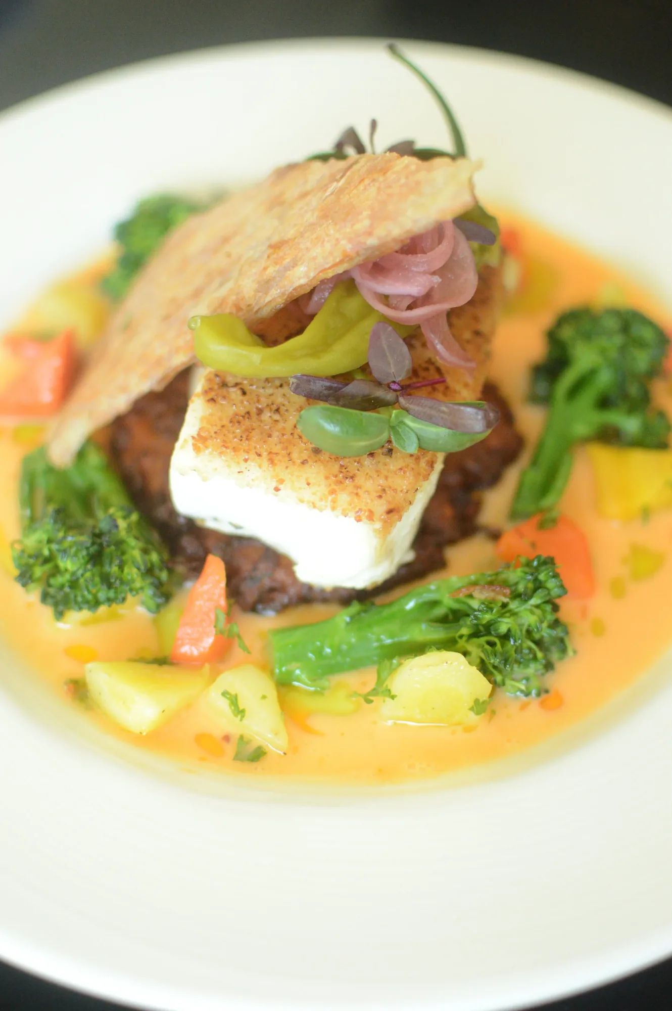 A seared fillet of fish over vegetables in a pale butter sauce.