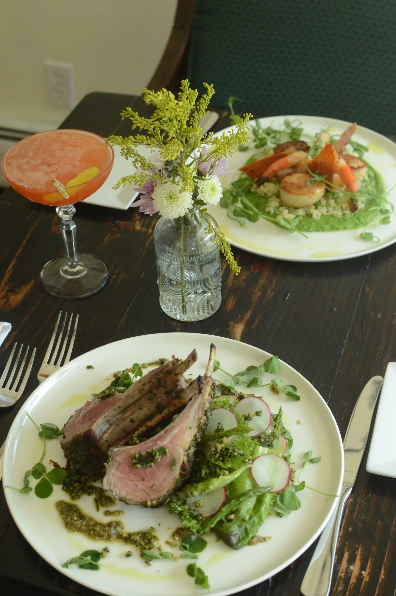 A set table with a plated main, a salad and a cocktail.